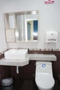 uma casa de banho com um lavatório, um WC e um espelho. em Hotel SMIR em Huaquillas