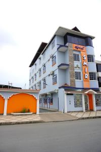 Hotel SMIR في Huaquillas: فندق بمبنى برتقالي وبيض