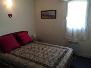 - une chambre avec un lit doté d'un oreiller rouge et d'une fenêtre dans l'établissement Résidence Les Bains - Charmant T3 à deux pas de la plage du Val André. MAE-6644, à Pléneuf-Val-André
