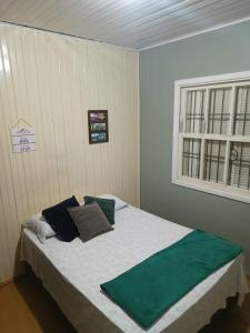 Un dormitorio con una cama con almohadas verdes y una ventana en Casarão das Figueiras, en Caxias do Sul