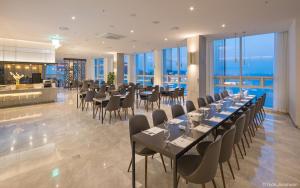 uma sala de jantar com mesas, cadeiras e janelas em Grab The Ocean Songdo em Busan