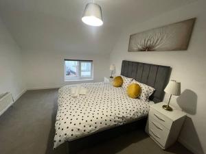 a bedroom with a bed with yellow pillows on it at 2 bedrooms haven near NEC, Airport in Curdworth