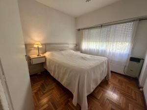 a bedroom with a white bed and a window at Depto para 4 a 4 cuadras de la playa in Mar del Plata