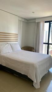 a bedroom with a large white bed and a window at Flat de dois quartos Number One in São Luís