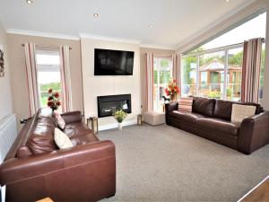 a living room with two brown leather couches and a fireplace at 2 Bed in Lochwinnoch 55854 in Kilmacolm