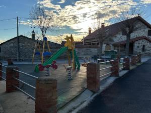 un parque infantil con tobogán y columpios en La Casona Medieval, en Malillos