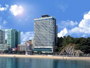 a tall building in front of a beach with buildings at Grab The Ocean Songdo in Busan