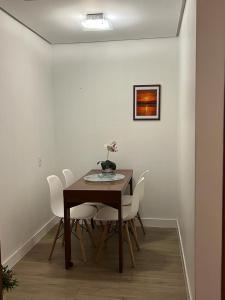 阿雷格里港的住宿－Flat espaçoso e confortável no Piazza Navona，一间带桌子和白色椅子的用餐室