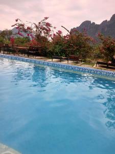 uma piscina azul com bancos e montanhas ao fundo em Riverside Garden Hostel em Vang Vieng
