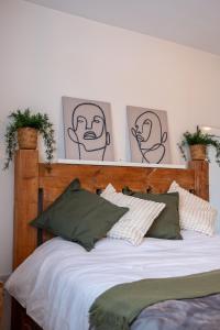 a bed with a wooden headboard with four pictures on the wall at Lovely family home in Rainham, Kent in Rainham