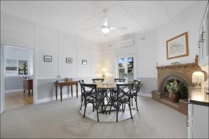 a dining room with a table and chairs and a fireplace at Lil's Cottage in Cessnock