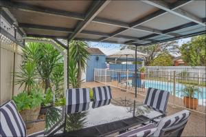 a patio with a table and chairs and a pool at Lil's Cottage in Cessnock