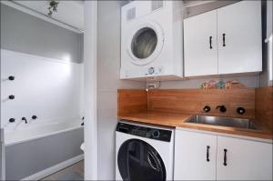 a kitchen with a washing machine and a sink at Lil's Cottage in Cessnock