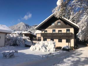 ein schneebedecktes Haus mit Bergen im Hintergrund in der Unterkunft Gästehaus Staller in Ruhpolding