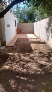 a backyard with a white wall and a brick driveway at el escondido in Villa Cura Brochero