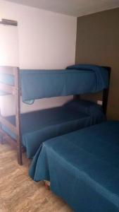 two bunk beds in a room with blue sheets at el escondido in Villa Cura Brochero