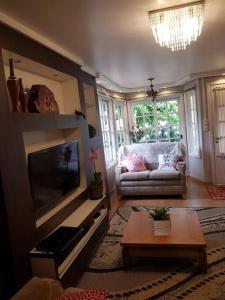 un salon avec une télévision et un canapé dans l'établissement Casa Mimosa, à Gramado