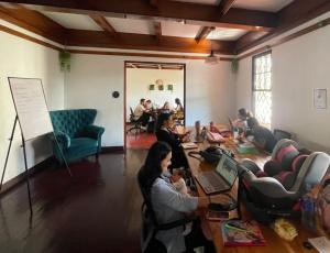 un grupo de personas sentadas alrededor de una mesa en una habitación en Costa Rica Guesthouse, en San José