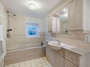a bathroom with a sink and a tub and a mirror at 5 Bed in Aberdovey 90493 in Aberdyfi