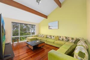 sala de estar con sofá verde y TV en Serene Mountain Haven with Scenic Balcony & Garden en Wentworth Falls