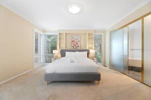Un dormitorio con una gran cama blanca y una ventana en Serene Mountain Haven with Scenic Balcony & Garden en Wentworth Falls