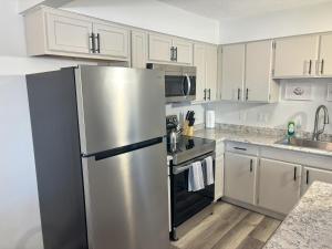 cocina con armarios blancos y nevera de acero inoxidable en Gorgeous Remodeled Classy Family Apartment, en Granite City