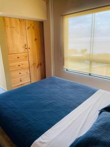 Un dormitorio con una cama azul y una ventana en La Casa del Pato, en Los Órganos