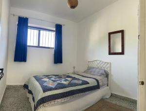 um quarto com uma cama e uma janela com cortinas azuis em Chalet en Playa Bahía Algeciras em Palmones