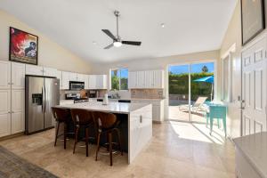 a kitchen with white cabinets and a island with bar stools at The Palms- Pool Jacuzzi and Pet Friendly in Palm Springs