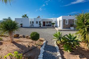 a white house with palm trees in front of it at Villa near San Antonio sleeps 10 in Ses Paisses