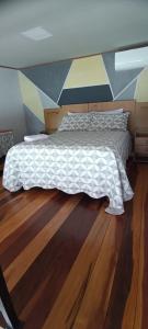Bett in einem Zimmer mit Holzboden in der Unterkunft Casa do Maycon in Mangaratiba
