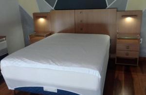 Schlafzimmer mit einem großen weißen Bett und Holzböden in der Unterkunft Casa do Maycon in Mangaratiba