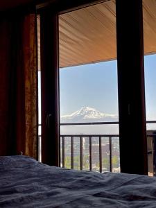 1 dormitorio con vistas a la montaña desde una ventana en Роскошная двухуровневая квартира Luxurious duplex apartment, en Ereván