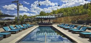 a swimming pool with lounge chairs and a swimming poolvisorvisor at Viceroy Snowmass in Snowmass Village