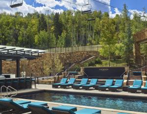 a pool with blue lounge chairs and a ski lift at Viceroy Snowmass in Snowmass Village