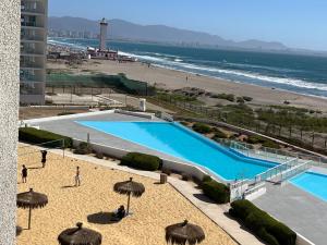 uma grande piscina ao lado de uma praia com guarda-sóis em Resort Laguna del mar em La Serena