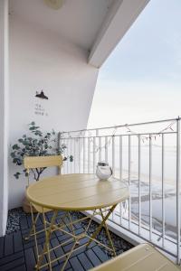 a yellow table and chairs on a balcony with the ocean at 영종도 구읍뱃터 오션뷰-Luxe 베드,넷플릭스, 사운드바, 식물테리어, 무료주차 in Incheon