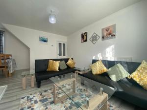 uma sala de estar com sofás pretos e uma mesa de vidro em Comfy & Affordable home - Sleeps 7, free off-street parking near City centre, Cadbury World & Cannon Hill Park em Kings Norton