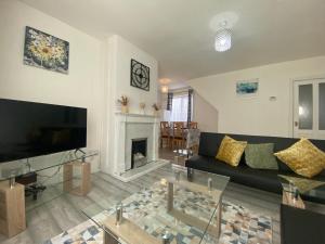 uma sala de estar com um sofá preto e uma lareira em Comfy & Affordable home - Sleeps 7, free off-street parking near City centre, Cadbury World & Cannon Hill Park em Kings Norton