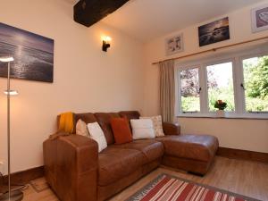 a brown leather couch in a living room with windows at 1 Bed in Kilve KILVE in Kilve
