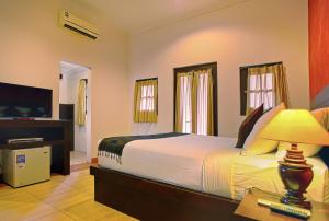 a bedroom with a large bed and a television at Puri Sading Hotel in Sanur