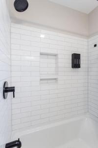 uma casa de banho em azulejos brancos com uma banheira e um lavatório. em Swamp Rabbit l 3 Mi to dwtn GVL l Bikes l Park Pass l King em Greenville