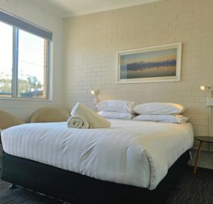 Un dormitorio con una cama grande con sábanas y almohadas blancas. en Sea Lake Motel, en Sea Lake
