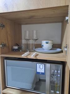 eine Mikrowelle in einem Schrank mit Teller und Brille in der Unterkunft Ultra mini suite privada con baño in Guayaquil