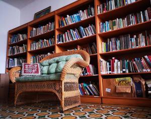 a wicker chair sitting in front of a book shelf at Hostel Casa Ridgway in San José