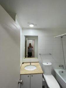 a man taking a picture of a bathroom with a sink and toilet at Departamento Cómodo en Santiago in Santiago