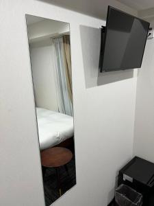 名古屋的住宿－BRILLIANCE Hotel，一张床铺和一台电视机的镜子