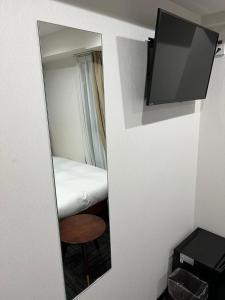 a mirror in a room with a bed and a television at BRILLIANCE Hotel in Nagoya