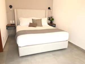 duże białe łóżko w pokoju z dwoma stołami w obiekcie Urban Chapalita w mieście Guadalajara
