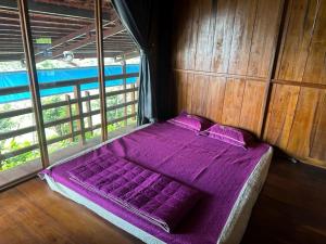 Cama en habitación con sábanas y almohadas moradas en Khu Du lịch Nông trại Hải Đăng trên núi, en Gia Nghĩa